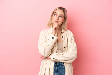 Young caucasian woman isolated on pink background and looking up