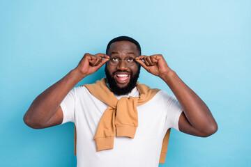 Photo of smiling excited man look up see glasses advertisement laughing isolated on blue color...