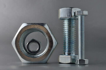 composition of new bolts and nuts of different sizes on a gray background.