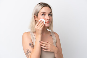 Young caucasian woman isolated on white background with cotton pad for removing makeup from her face