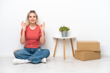 Young woman moving in new home among boxes isolated on white background showing an ok sign with fingers