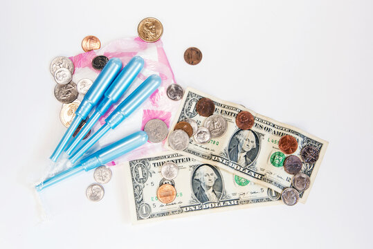 Tampones y compresas junto a monedas y billetes de d&oacute;lar sobre un fondo blanco. Concepto de precios e impuestos de los productos de higiene femenina