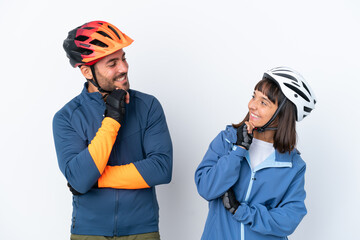 Young cyclist couple isolated on white background looking looking at each other