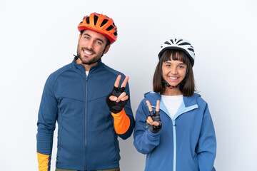 Young cyclist couple isolated on white background smiling and showing victory sign