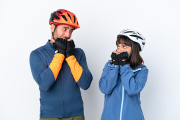 Young cyclist couple isolated on white background is a little bit nervous and scared putting hands to mouth