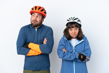 Young cyclist couple isolated on white background making doubts gesture while lifting the shoulders