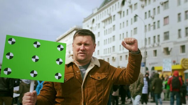 Protesting activist hold green mock up placard, chroma key banner with motion tracking points. Empty text space, blank place for advertisement template. Political demonstration poster board on rally.