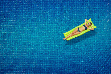 Enjoying suntan. Vacation concept. Top view of slim young woman in bikini on the yellow air...