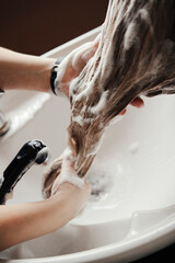 The hairdresser washes the hair of a fair-haired girl