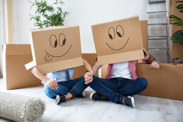 Funny happy couple sitting on floor wearing cardboard boxes