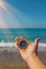Compass in hands against the background of the sea. Selective focus.