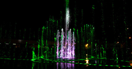 Green-pink jets of the fountain at night.