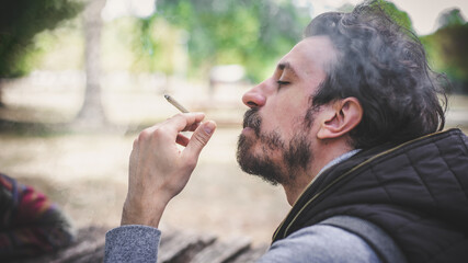 Closeup detail view of man smoke marijuana ganja joint cigarette