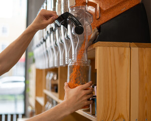 A man fills a jar with red lentils. Selling bulk goods by weight in an eco store. Trade concept...