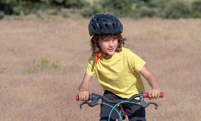 little boy with safety helmet has fun and smiles while riding his bike. leisure and free time concept