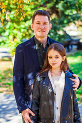 Portrait of a father and teenage daughter posing in autumn park