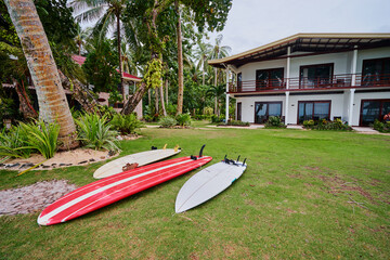Tropical villa with surf boards on the grass.