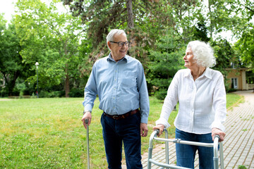 Elder people using walking cane and a walker for a gentle stroll in the park