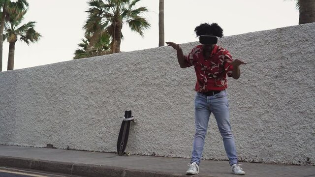 Happy Afro man having fun playing with virtual reality glasses during summer time - Technology concept