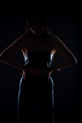 Silhouette of girl posing with her hands on the hips