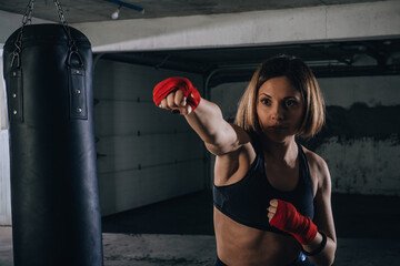 Young beautiful female preparing her bandages for kicking the boxing bag