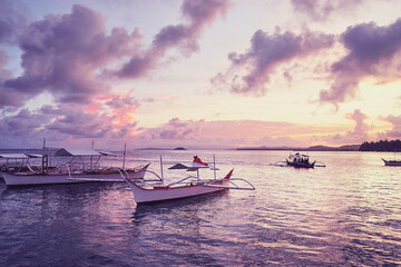 Fototapeta na wymiar Beautiful colorful sunset on the seashore with fishing boats. Philippines, Siargao Island.
