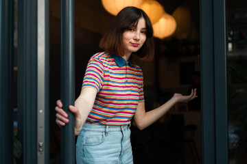 A cute waitress is at the entrance door, inviting you to come to the bar.