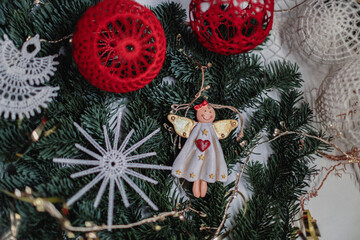 Christmas angels and balls with weaving in the macrame style on the background of a Christmas tree, handmade decor in an eco-style, hands close-up, top view