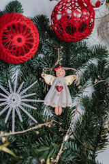Christmas angels and balls with weaving in the macrame style on the background of a Christmas tree, handmade decor in an eco-style, hands close-up, top view