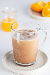 Cold vegan moccacino coffee with chocolate and orange juice in a glass mug.