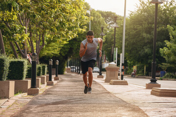 Fototapeta premium Silhouette of young man running sprinting on road. Fit runner fitness runner during outdoor workout with sunset background.