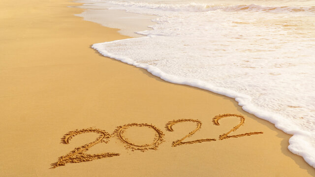 2022 happy New Year coming concept. White waves are lapping towards the sand beach.