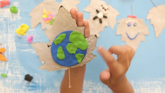Child sculpturing plasticine planet for earth day. Protection of environment, Save our planet. Ecology concept. Concept of art learning and education
