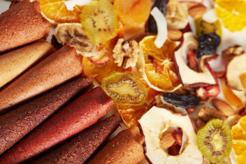 Above view of tasty fruit and berries lozenge different colors orange, dried apricot, raisins, walnuts, dried apples and kiwi on white background. Concept of healthy assorted dried fruit for snacks.