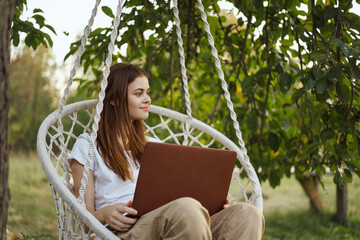 woman with laptop outdoors resting in hammock internet