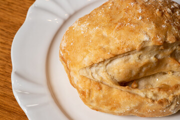 French bread, served on a white plate on a wooden table for breakfast, close up photo
