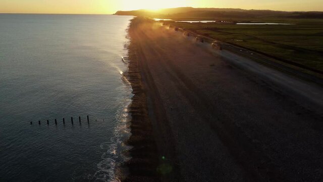 Trucks moving shingle on edge of beach.