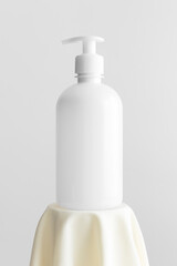 White cosmetic liquid soap dispenser bottle mockup on the yellow textile.