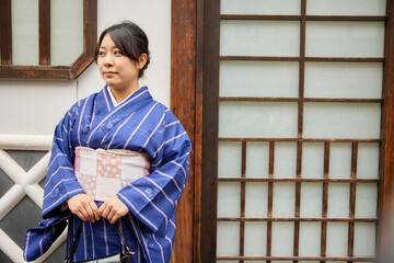 日本屋敷の前に立つ着物を着た日本人女性の上半身写真