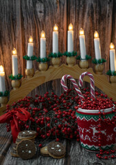Moscow, Russia, December 2021, Christmas card, background, a cup in a sweater. red beads and candies on the background of a Christmas wreath of red berries and a candlestick