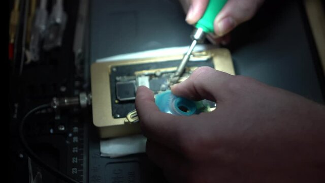 Close up of man microsoldering and repairing a board in a repair shop