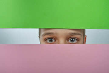 portret chłopaka ukrytego za kolorowym tłem  - obrazy, fototapety, plakaty