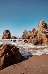 Obraz premium Cliffs and rocks on the Atlantic ocean coast - Praia da Ursa beach, Portugal.