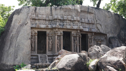 The cave temple is carved in stone and has sculptures and statues. Located on rocky and scenic backgrounds