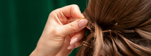 Fototapeta premium Hairdresser makes hairstyles for a young woman in beauty salon close up