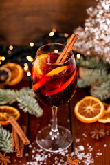A glass of mulled wine on the wooden table surrounded by Christmas decorations. Festive winter...