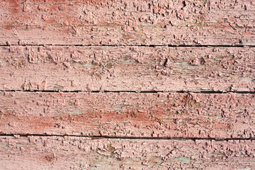 Wooden surface with cracked dirty pink paint