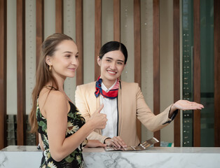 The charming young lady was pleased with the receptionist's advice on the hotel's services to the guests, Selective focus on the customer