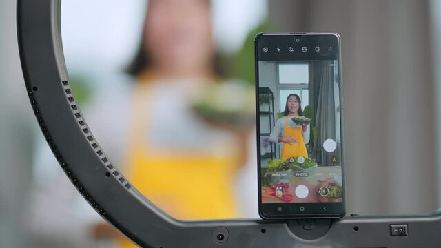 Attractive asian female vlogger lives streaming to all her follower to explain how to make healthy diet salad bowl for moning breakfast meal at home,asian female use smartphone to lives streaming her 