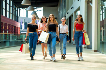Five happy young women are walking in the mall
